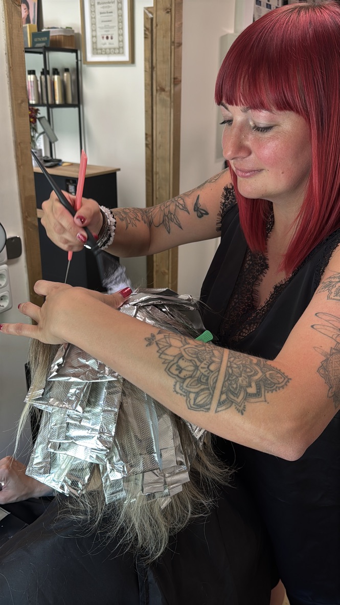 Foliensträhnen werden im Studio Glow Friseursalon in langes blondes Haar eingearbeitet